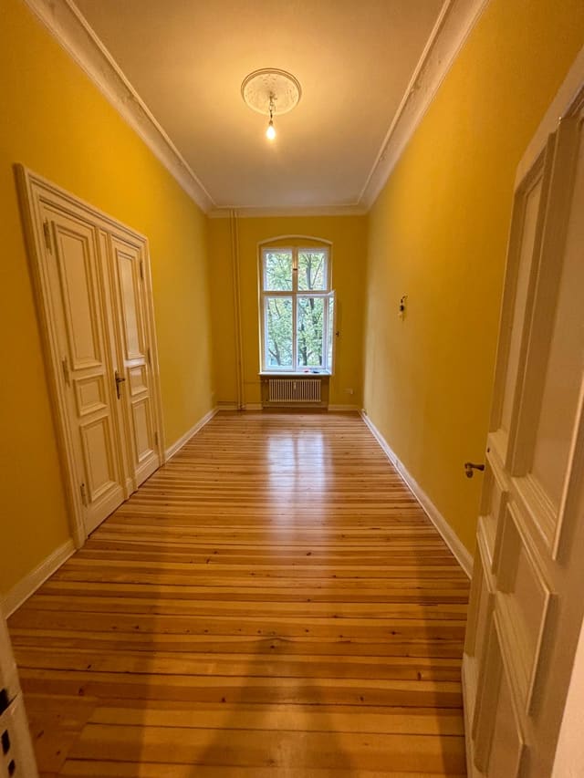 Long hallway with mustard-yellow walls and restored wood flooring