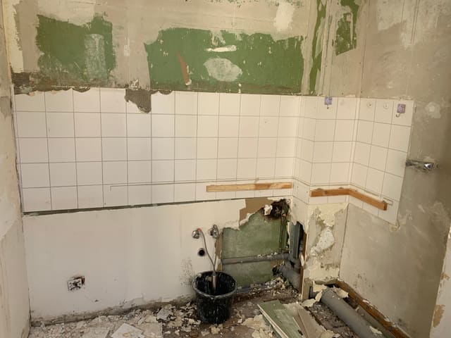 Bathroom mid-demolition with old tiles stripped back