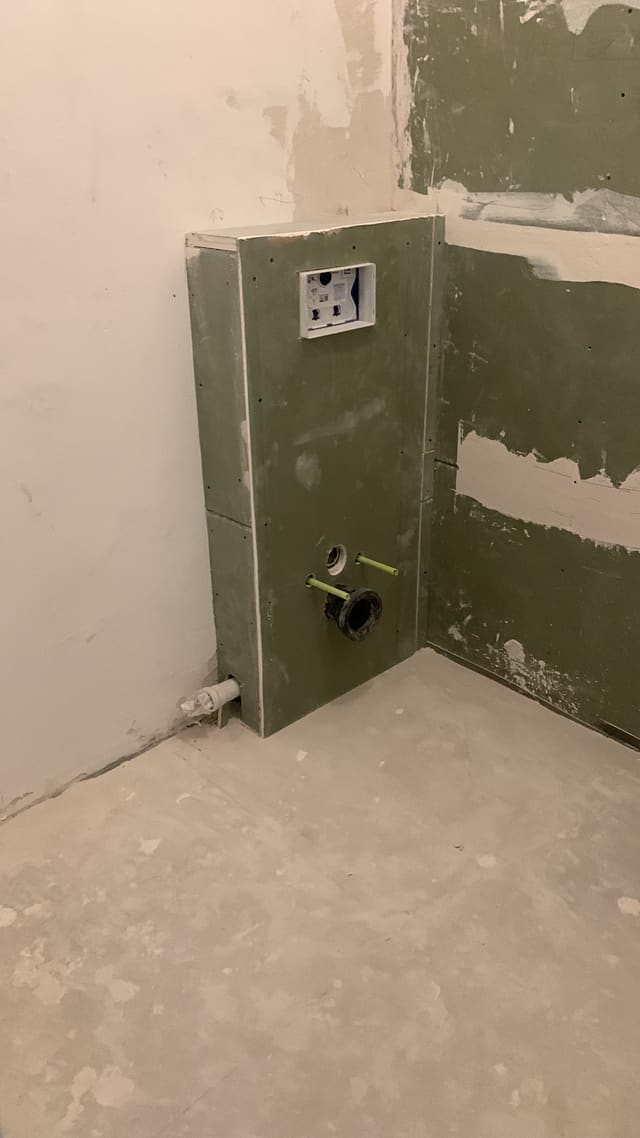 Electrical socket back box fitted into a plastered wall mid-renovation