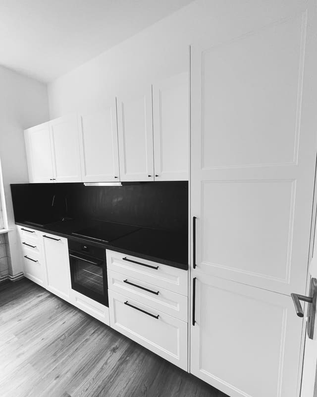 White fitted kitchen with black countertop and matching splashback