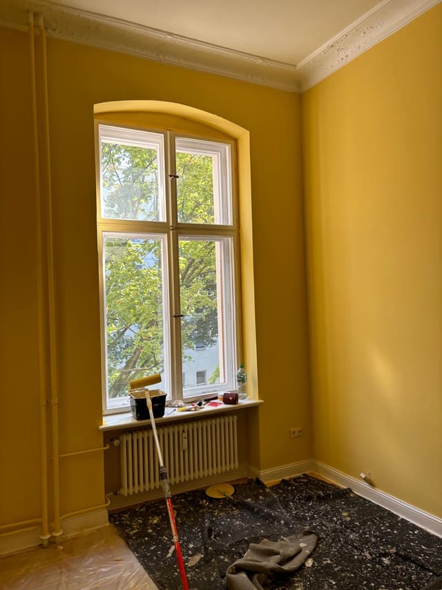 Freshly painted mustard-yellow room with original Berlin window and radiator
